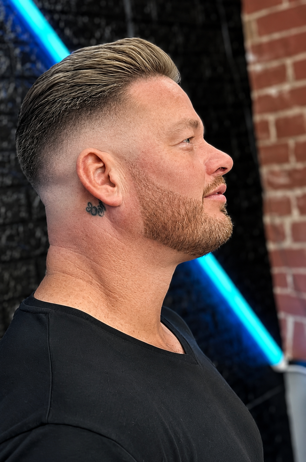 Sharp skin fade and full beard styling, side profile