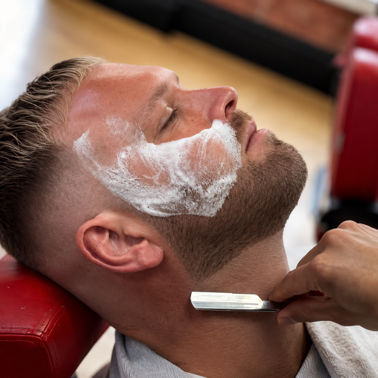 Barber shaping a beard with warm lather and a straight razor
